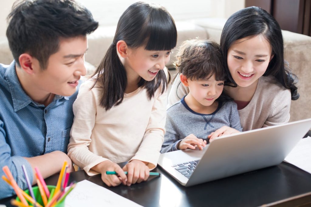 Family on laptop researching which cooling system is better - heat pumps or air conditioners